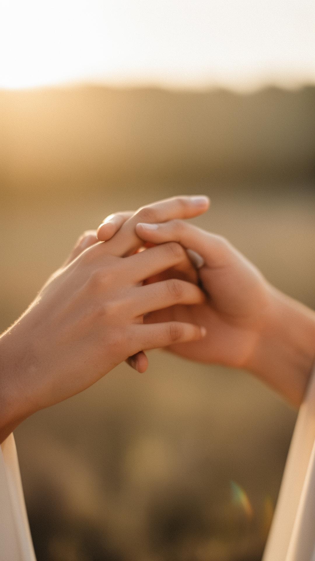 Two hands gently touching in warm golden hour light